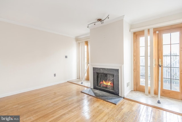 unfurnished living room featuring light wood-type flooring, baseboards, a fireplace, and ornamental molding