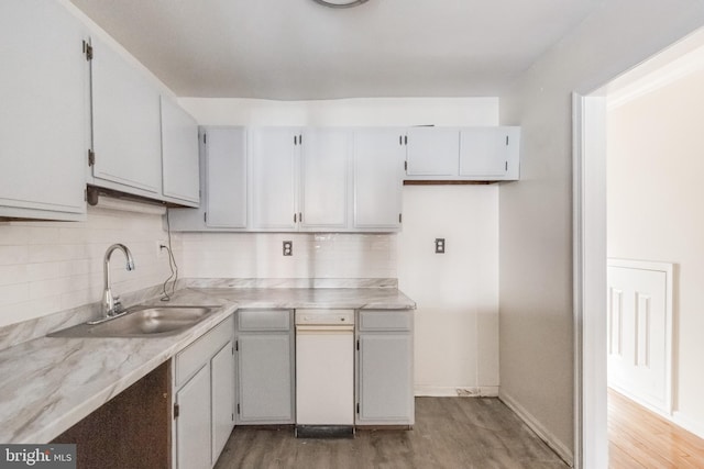 kitchen featuring decorative backsplash, light countertops, a sink, and light wood finished floors