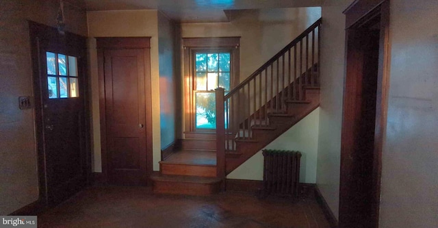 entrance foyer featuring radiator, stairway, and wood finished floors