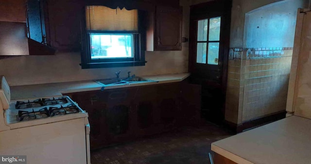 kitchen featuring light countertops, white gas range oven, and a sink