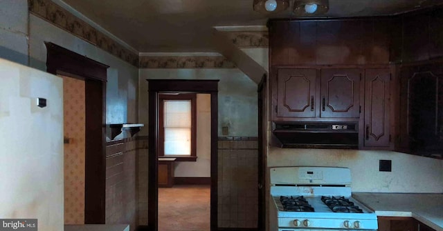 kitchen with white gas stove, light countertops, and under cabinet range hood