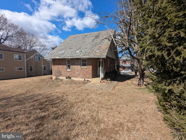 back of house featuring a high end roof, brick siding, and a lawn