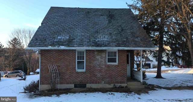 view of snow covered exterior featuring brick siding