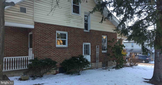 view of snowy exterior featuring brick siding