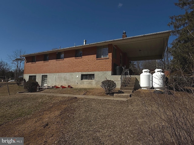 rear view of property featuring brick siding and an attached carport