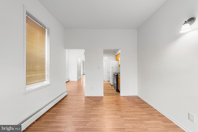 unfurnished room with baseboards, baseboard heating, and light wood-style floors