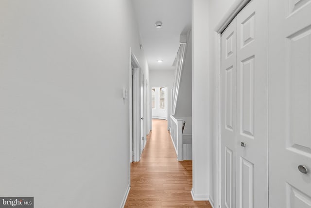 corridor featuring light wood-type flooring and baseboards