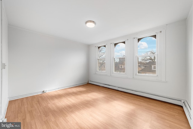 spare room with a baseboard heating unit and wood finished floors