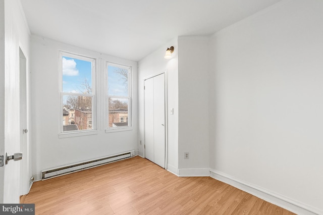 spare room featuring light wood-style flooring and baseboard heating