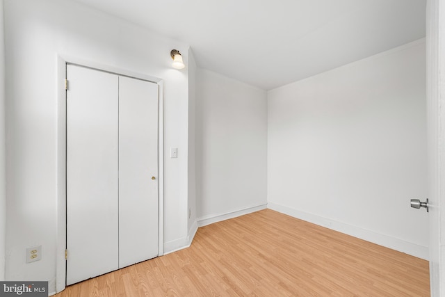 unfurnished bedroom featuring baseboards, a closet, and light wood-style floors