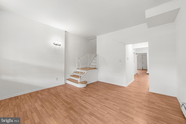 unfurnished living room with stairs, light wood-type flooring, baseboards, and a baseboard radiator