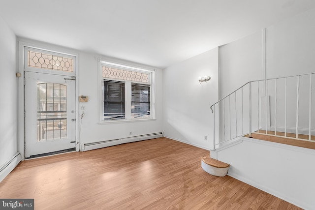 foyer entrance with a baseboard radiator, stairs, and wood finished floors