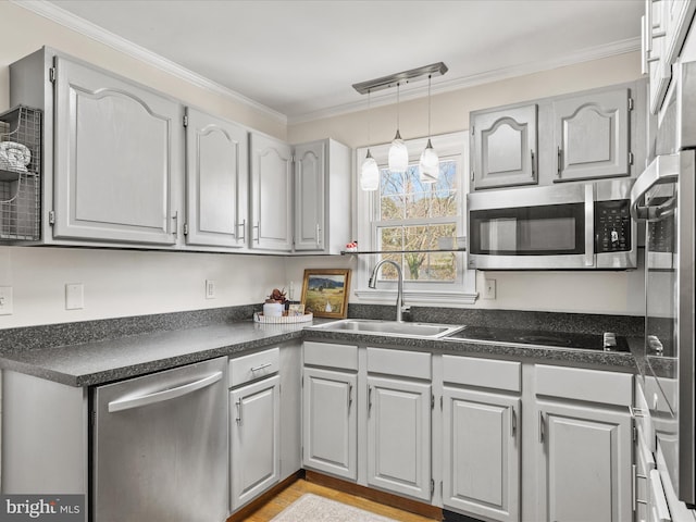 kitchen featuring a sink, ornamental molding, stainless steel appliances, pendant lighting, and dark countertops