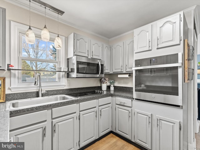 kitchen featuring dark countertops, crown molding, appliances with stainless steel finishes, and a sink