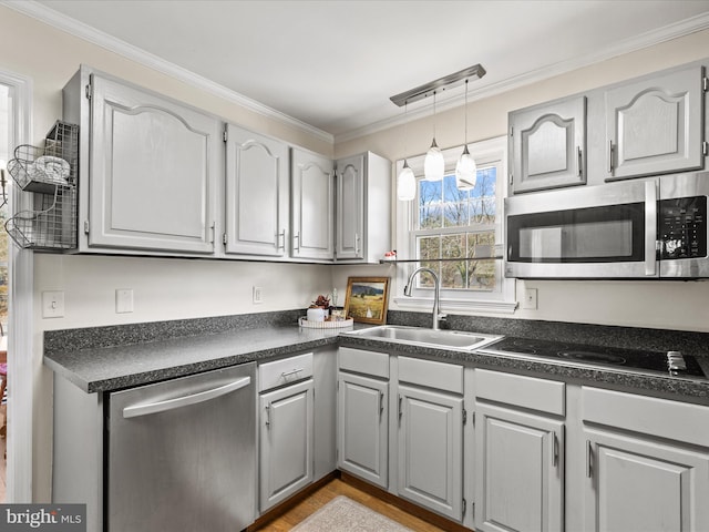 kitchen featuring dark countertops, crown molding, pendant lighting, stainless steel appliances, and a sink