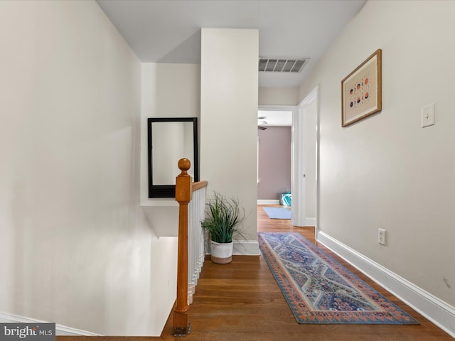 hallway with wood finished floors, visible vents, and baseboards