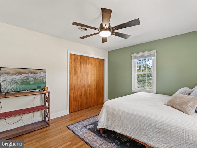 bedroom featuring a closet, ceiling fan, baseboards, and wood finished floors