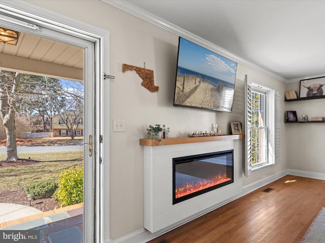 details featuring wood finished floors, visible vents, baseboards, a glass covered fireplace, and crown molding