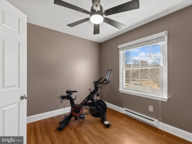 workout room with a baseboard heating unit, wood finished floors, baseboards, and a ceiling fan