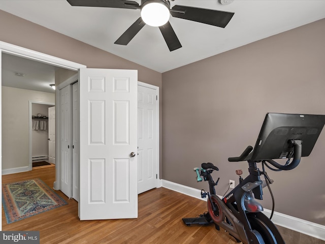 exercise area with wood finished floors, baseboards, a baseboard radiator, lofted ceiling, and ceiling fan