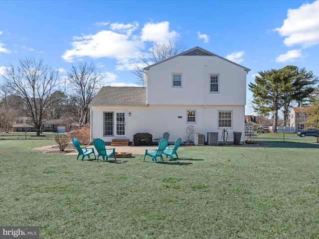 rear view of property featuring central AC unit, a lawn, and a shingled roof