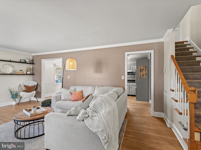 living area with stairway, crown molding, baseboards, and wood finished floors