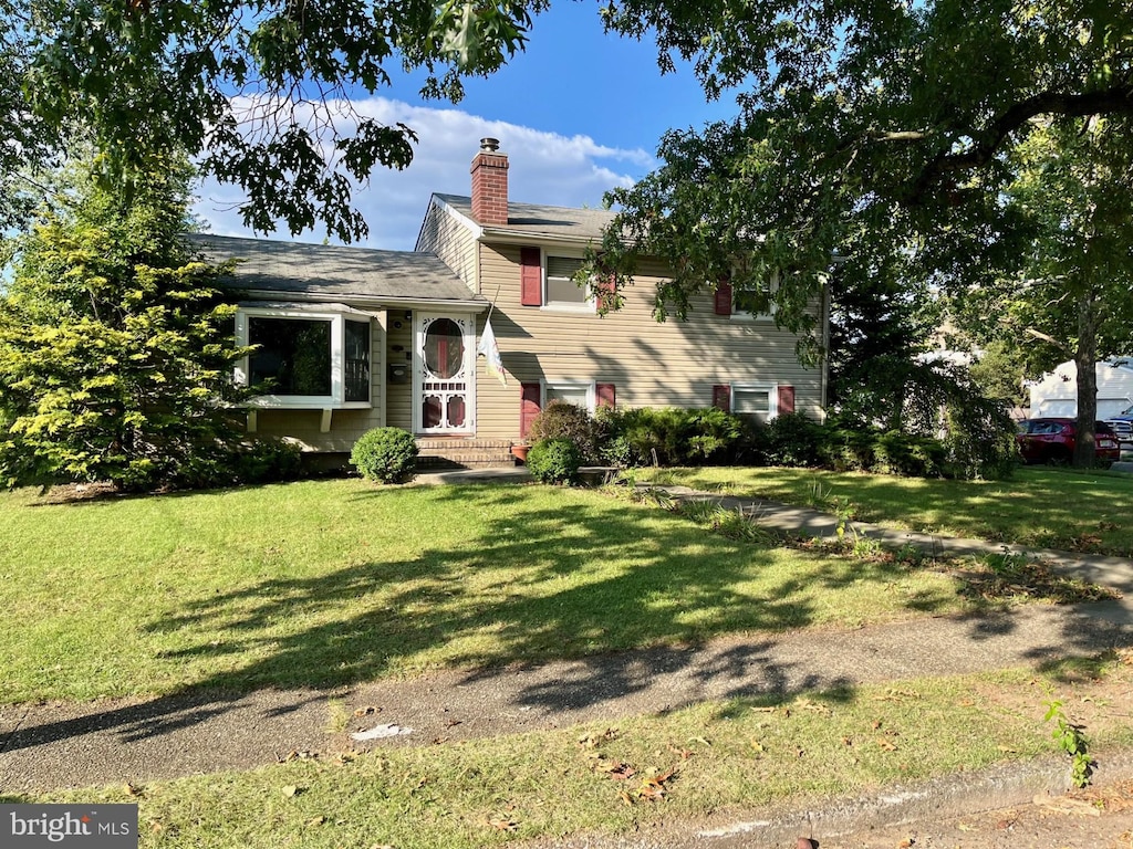 split level home featuring a chimney and a front lawn