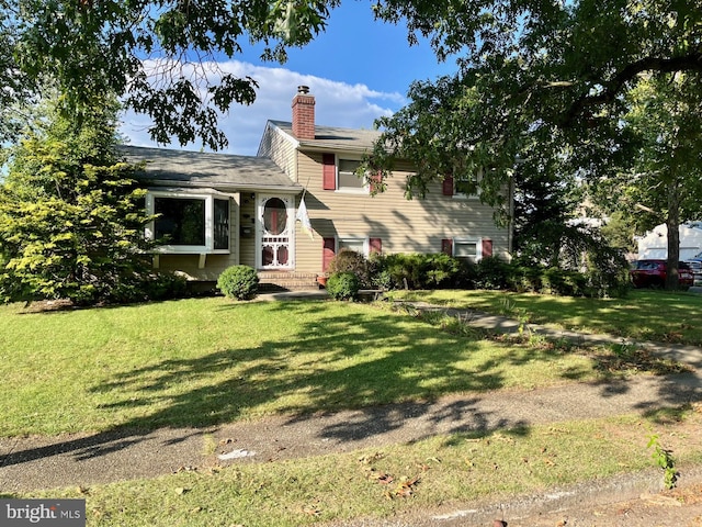 split level home featuring a chimney and a front lawn