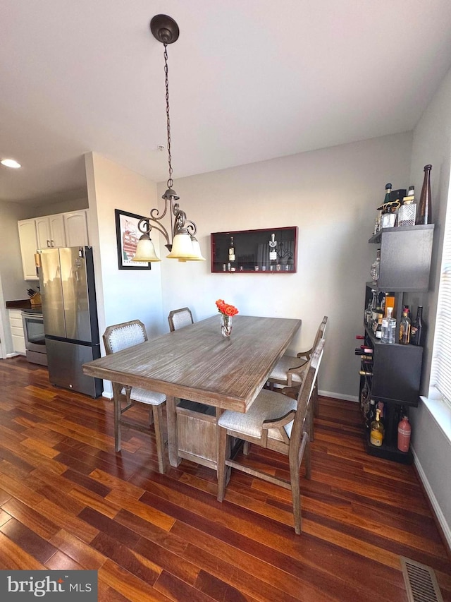 dining area with dark wood-type flooring, baseboards, and visible vents