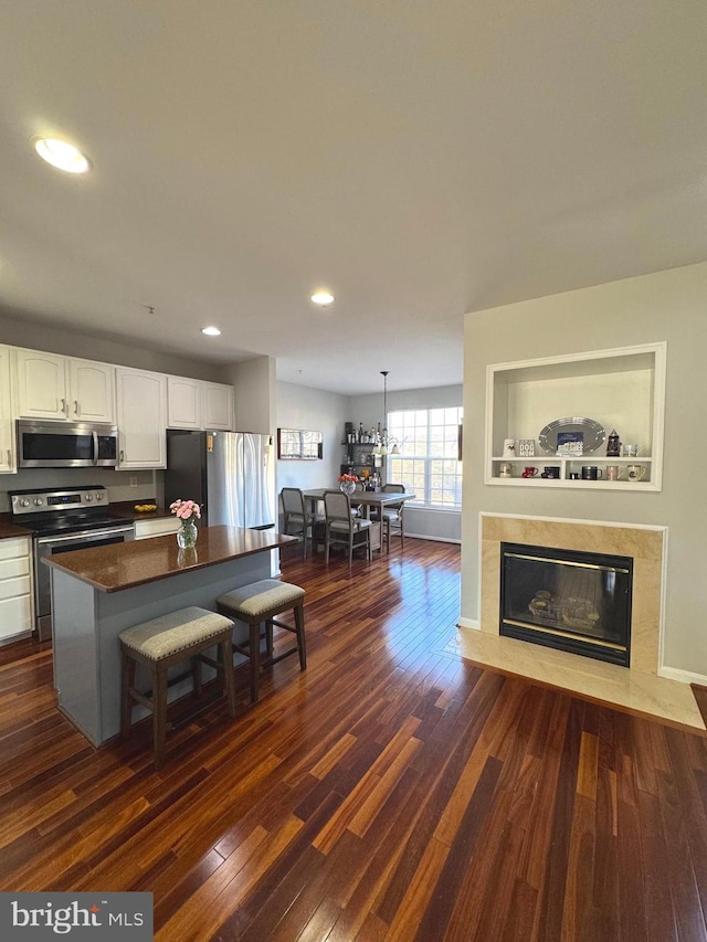 kitchen with dark countertops, white cabinets, dark wood-type flooring, and stainless steel appliances