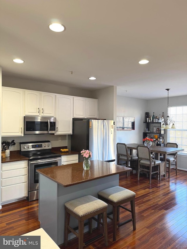 kitchen with dark countertops, appliances with stainless steel finishes, dark wood finished floors, and white cabinets