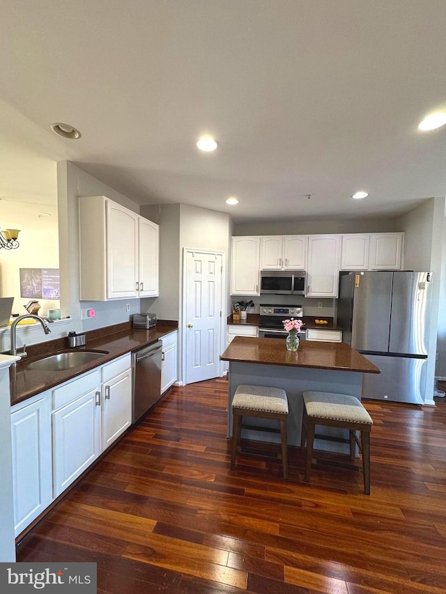 kitchen featuring dark countertops, appliances with stainless steel finishes, dark wood-type flooring, and a sink