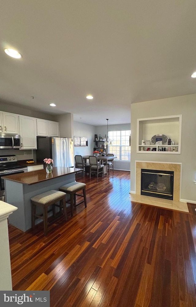 kitchen featuring a premium fireplace, dark wood finished floors, stainless steel appliances, white cabinetry, and dark countertops