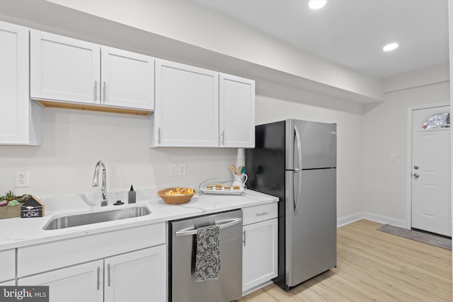 kitchen featuring light wood finished floors, stainless steel appliances, white cabinetry, a sink, and recessed lighting