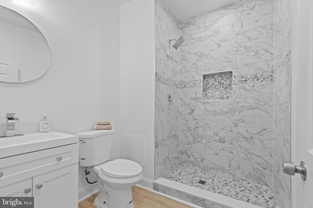 full bathroom with toilet, a stall shower, vanity, wood finished floors, and baseboards