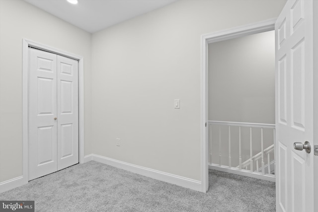 unfurnished bedroom featuring carpet floors, a closet, and baseboards