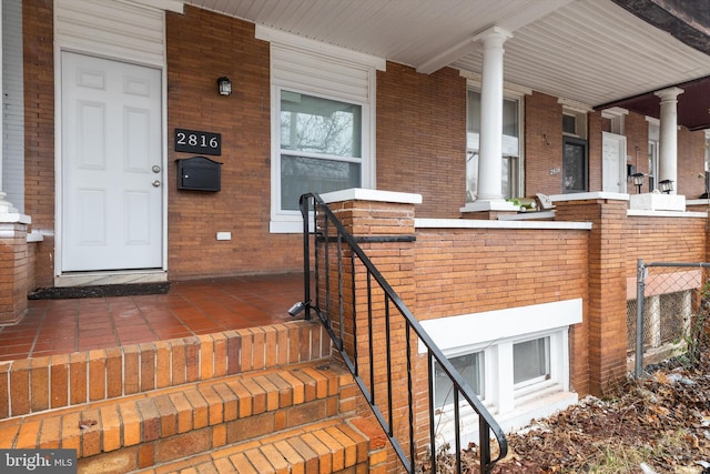 property entrance with covered porch and brick siding