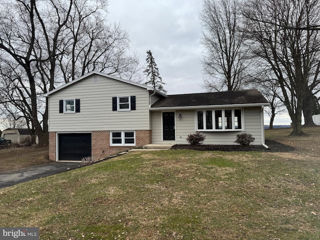 split level home with a front yard, an attached garage, brick siding, and driveway