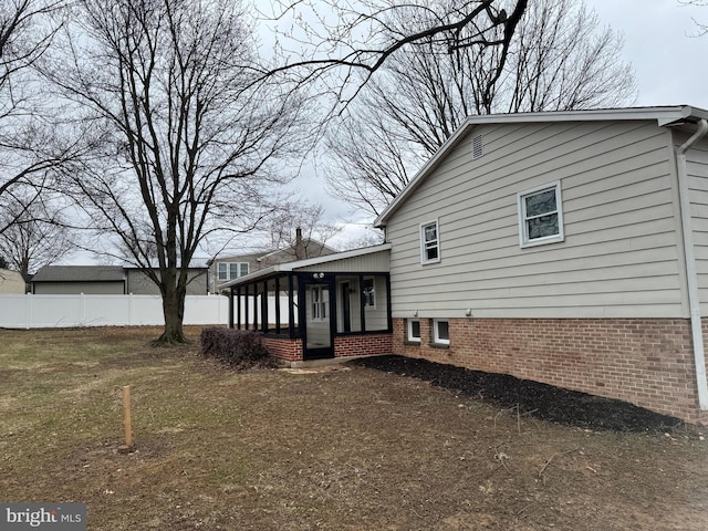 view of side of home featuring fence and a sunroom