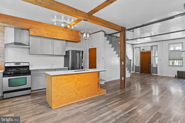 kitchen featuring wall chimney exhaust hood, stainless steel appliances, light countertops, and wood finished floors