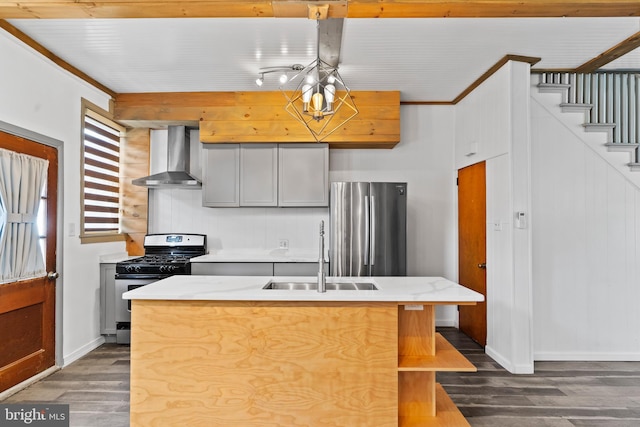 kitchen featuring an island with sink, dark wood-style floors, stainless steel appliances, wall chimney range hood, and a sink