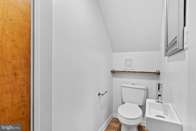 bathroom featuring lofted ceiling, baseboards, and toilet