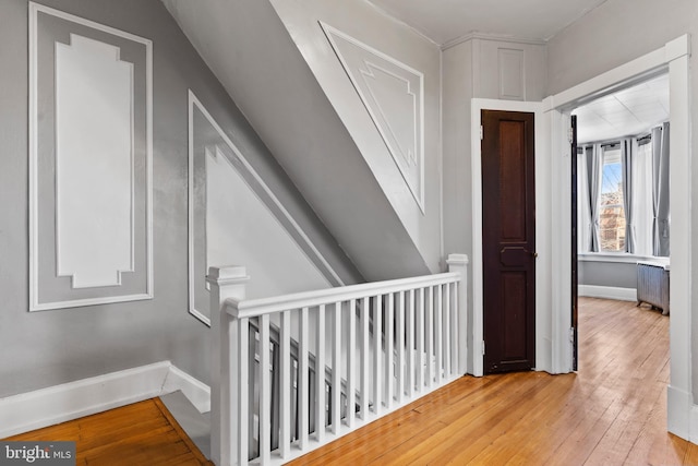 corridor with radiator, baseboards, and hardwood / wood-style floors