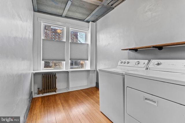 laundry area with radiator, separate washer and dryer, light wood-type flooring, laundry area, and baseboards