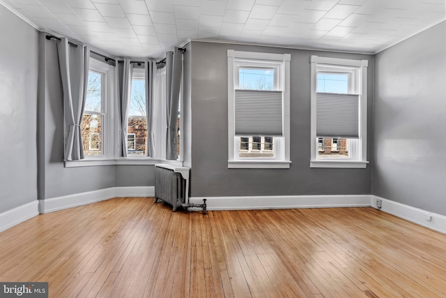 unfurnished room featuring hardwood / wood-style flooring, radiator heating unit, and baseboards