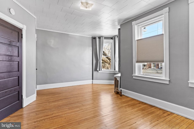 unfurnished room featuring wood-type flooring, baseboards, and crown molding