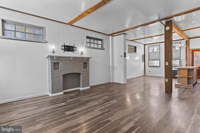 unfurnished living room with a fireplace, wood finished floors, beam ceiling, and baseboards