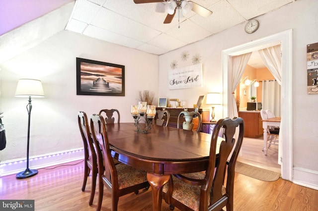 dining room featuring ceiling fan, a drop ceiling, light wood-style flooring, and baseboards