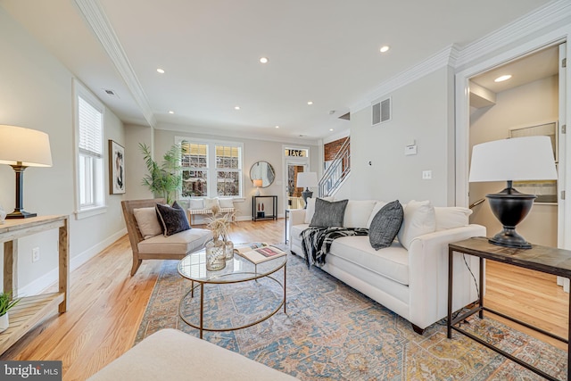 living room with visible vents, light wood-style flooring, and ornamental molding