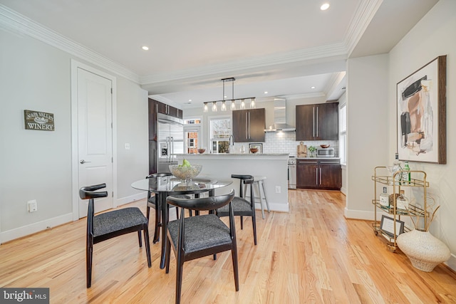 dining room featuring light wood finished floors, recessed lighting, crown molding, and baseboards